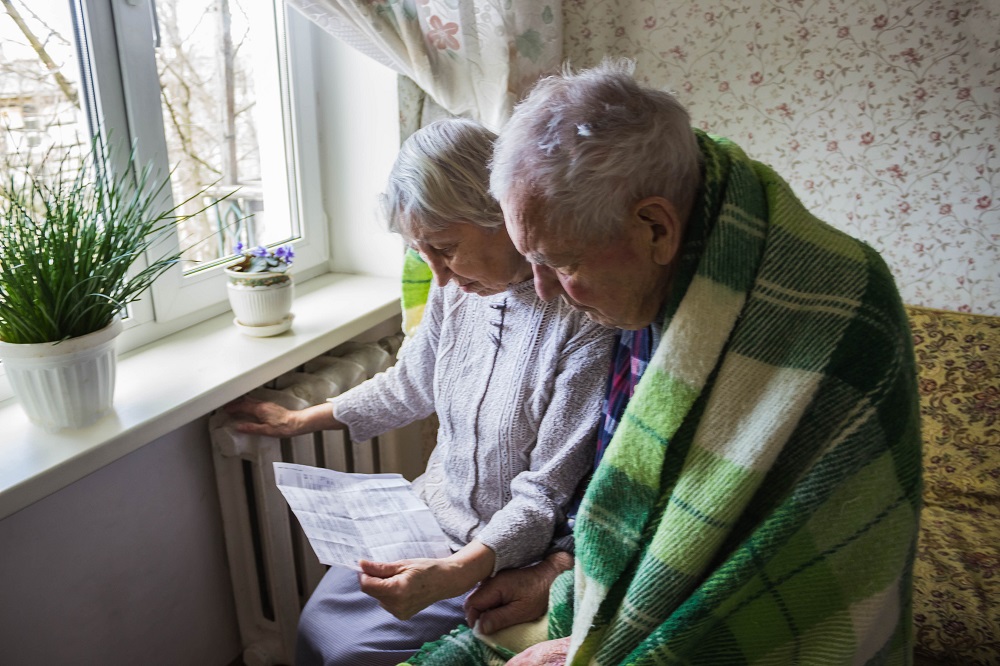 Woman holding cash in front of heating radiator. Payment for heating in winter. Selective focus.