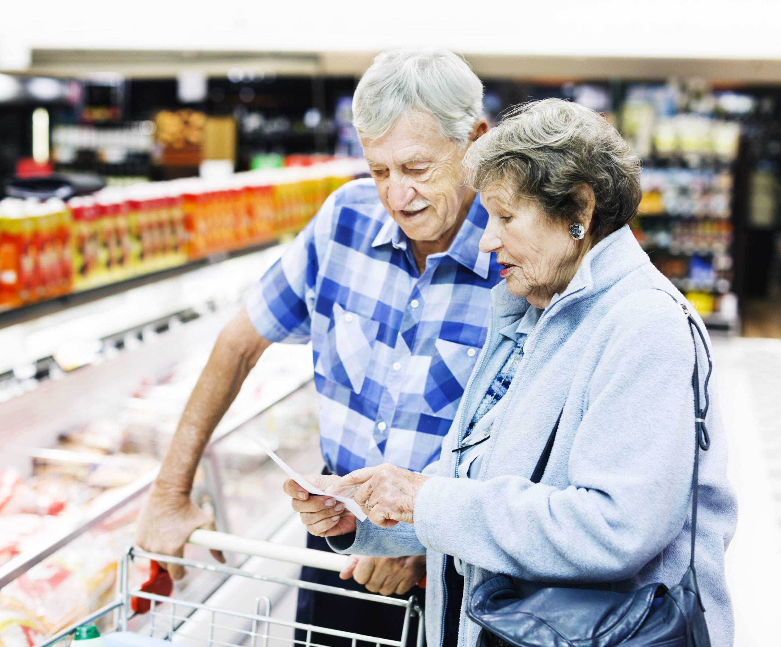 Cheerful senior couple check their shopping list in supermarket