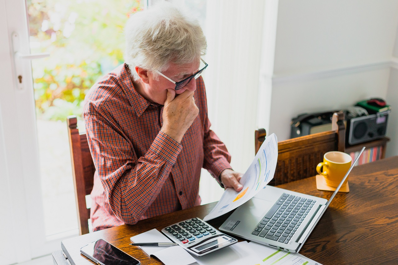 Worried senior man checking bills at home